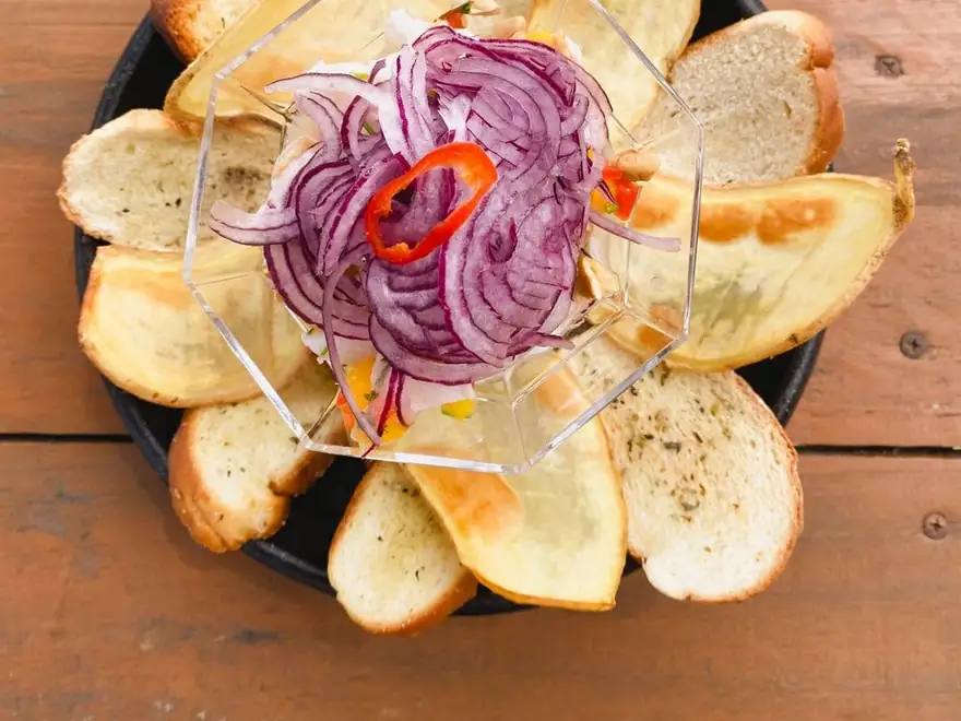 Ceviche do Bistrô com cebola roxa, cercado de torradas
