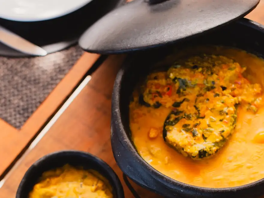 Moqueca baiana na panela preta, com arroz, farofa e pirão em potes